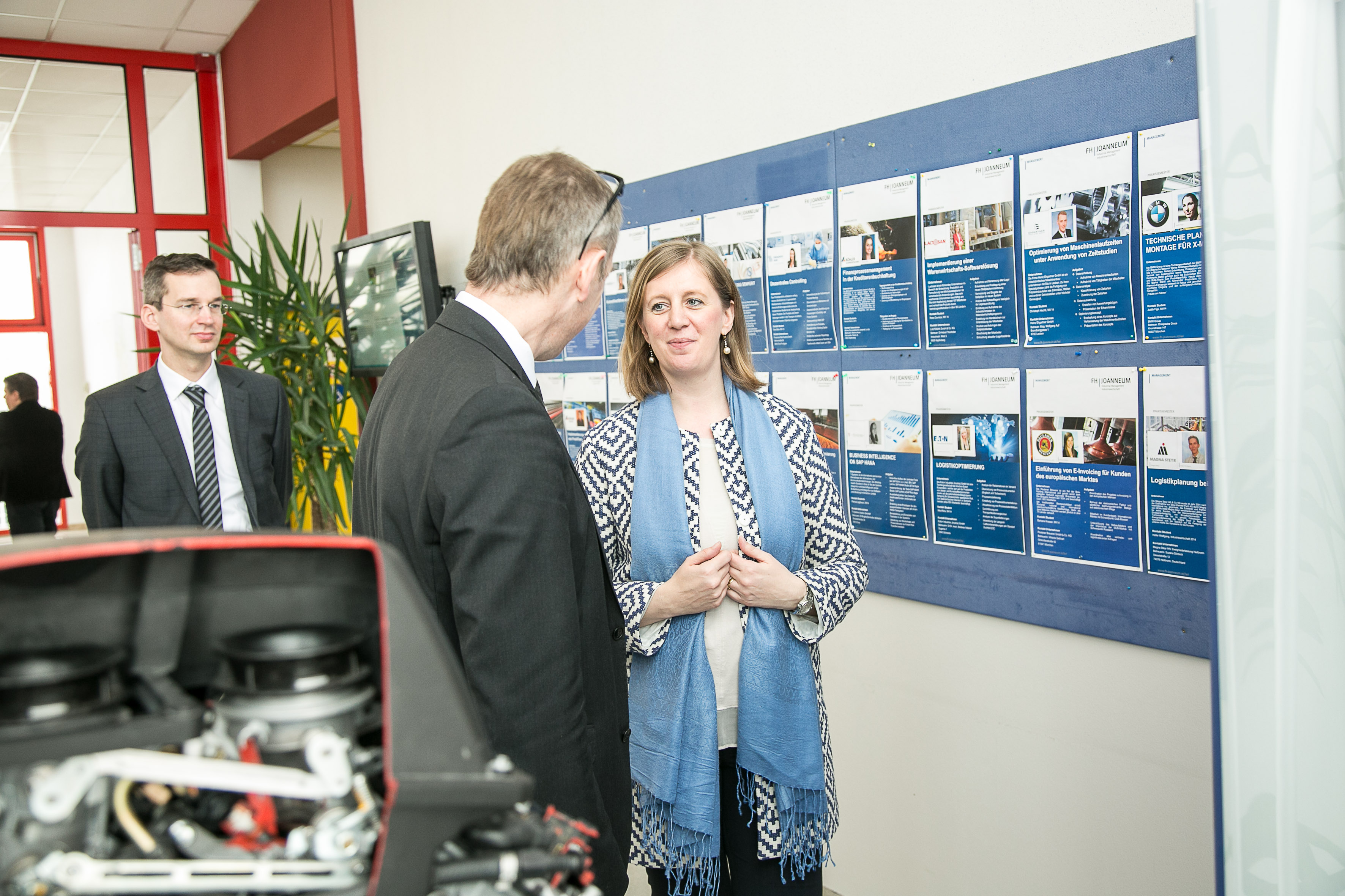 Zwei Personen im Gespräch vor einer Wand mit Projektbeschreibungen.