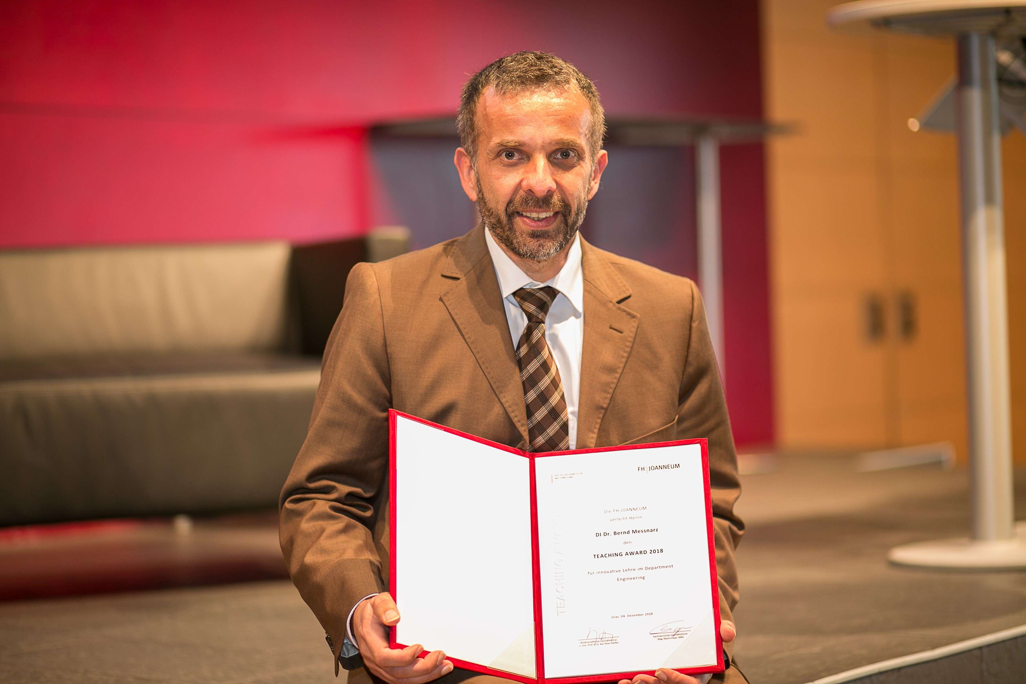 Bernd Messnarz hält den Teaching Award 2018 in die Kamera.