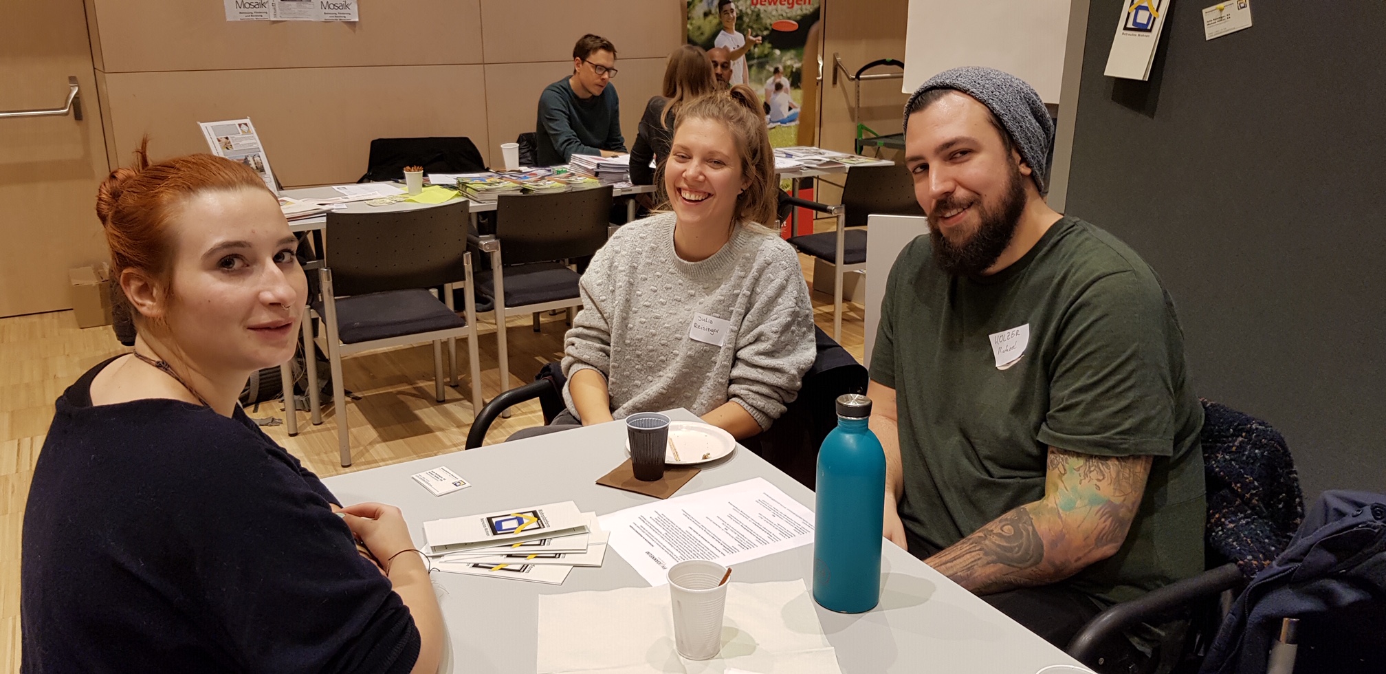 Teilnehmerinnen und Teilnehmer beim Kick-off-Meeting des Include-Projekts tauschen sich an einem Tisch aus.