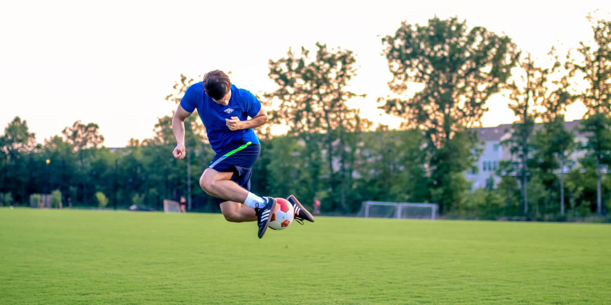 Fußballer hält Ball in der Luft zwischen den Füßen