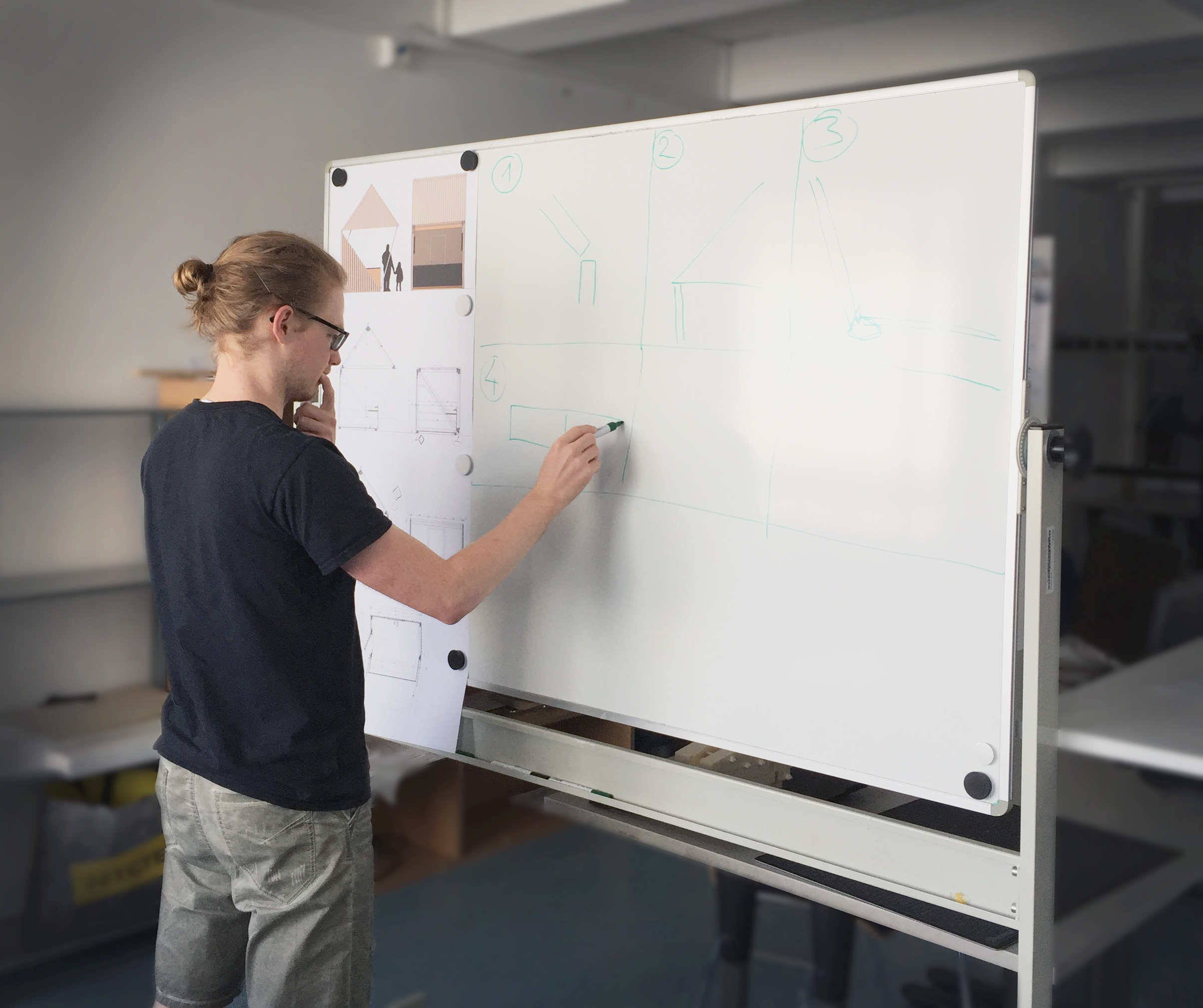 Peter Hintermayer steht vor einer weißen Tafel und hält einen Stift in der Hand, mit dem er etwas auf die Tafel zeichnet.